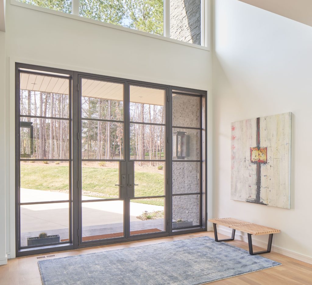 Modern glass front doors from the inside with painting on the right.