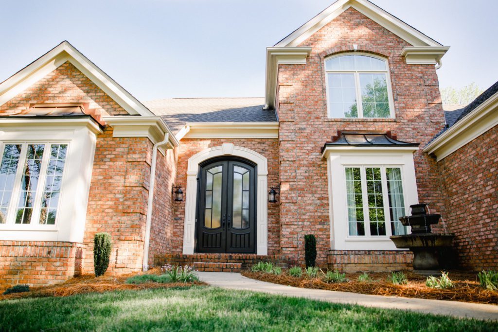 A brick home complete with custom traditional front doors.