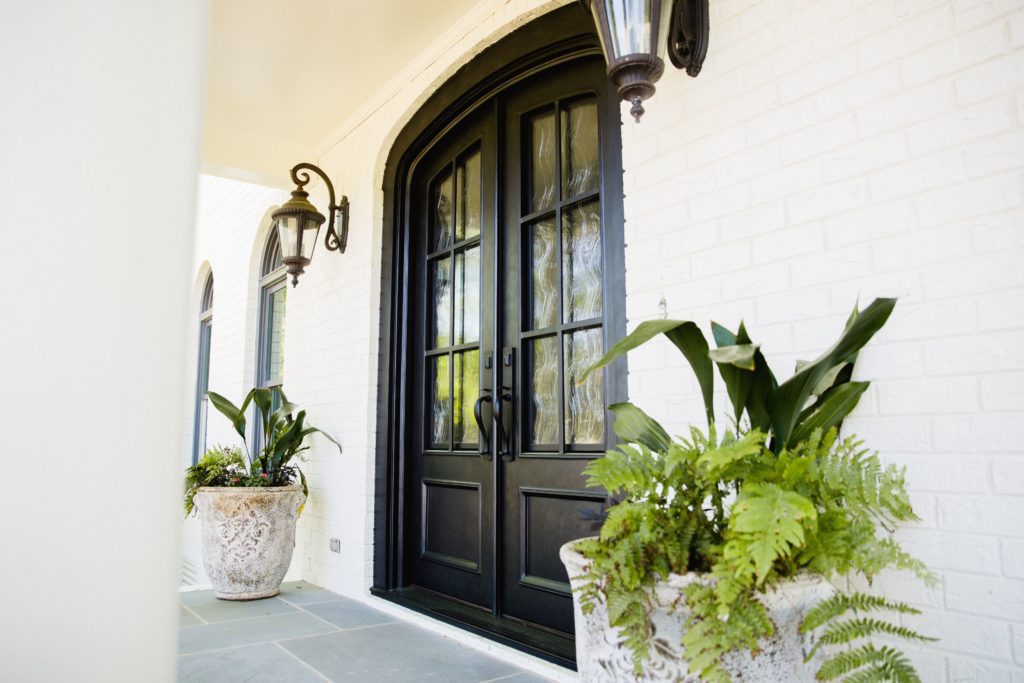 Traditional front door with glass and plants.