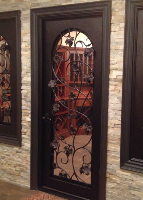 A custom, single panel ornate iron wine cellar door.