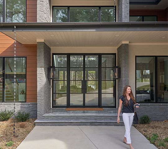 Woman walking in front of modern doors with glass.