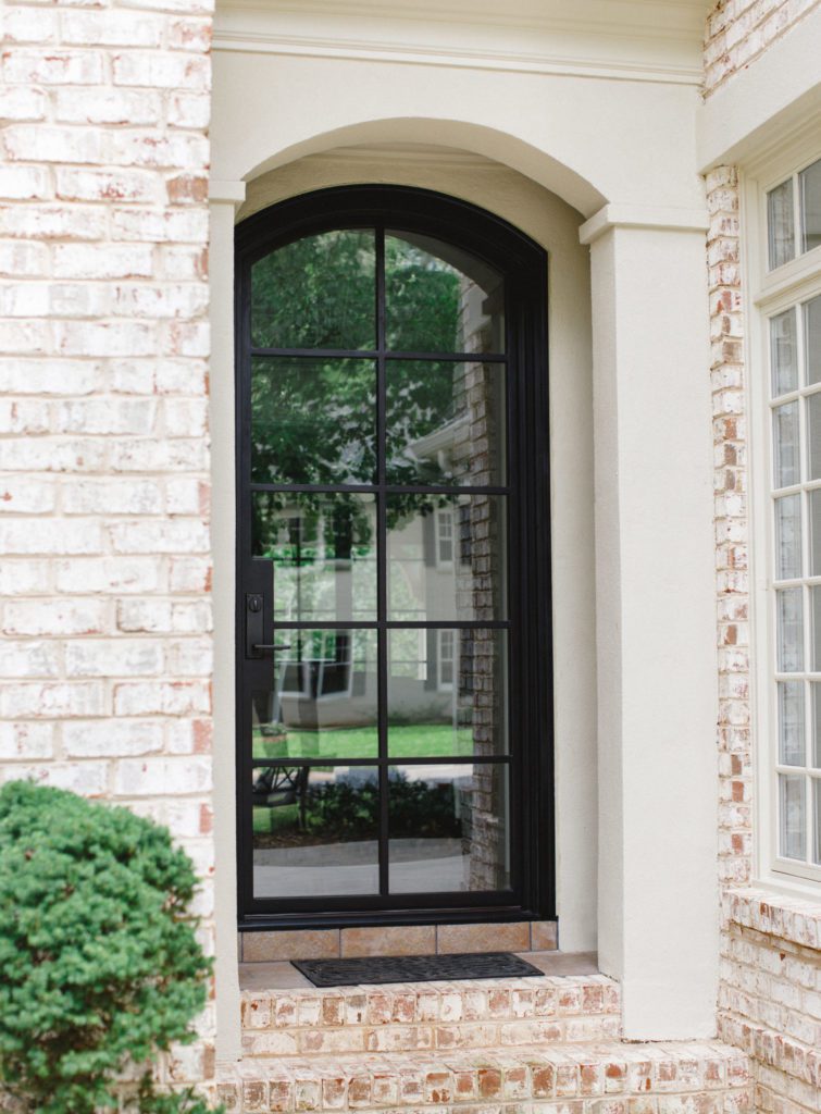 Curved modern door with clear glass and white brick exterior.