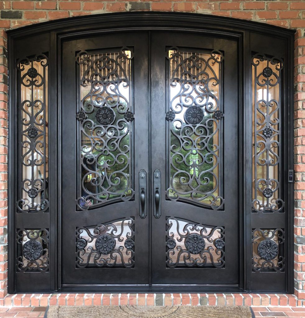 Elaborate and wide ornate front door with intricate scrollwork and sidelights.