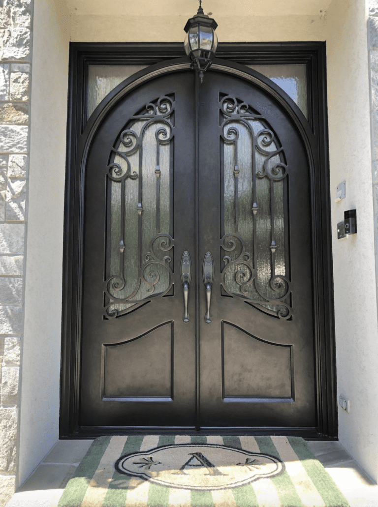 An ornate double iron door with unique scrollwork and two small transoms.