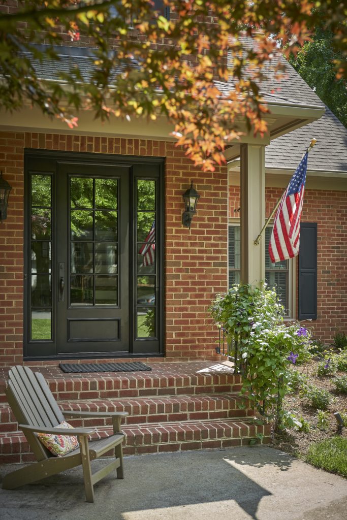 A brick home featuring a traditional door with two sidelights.