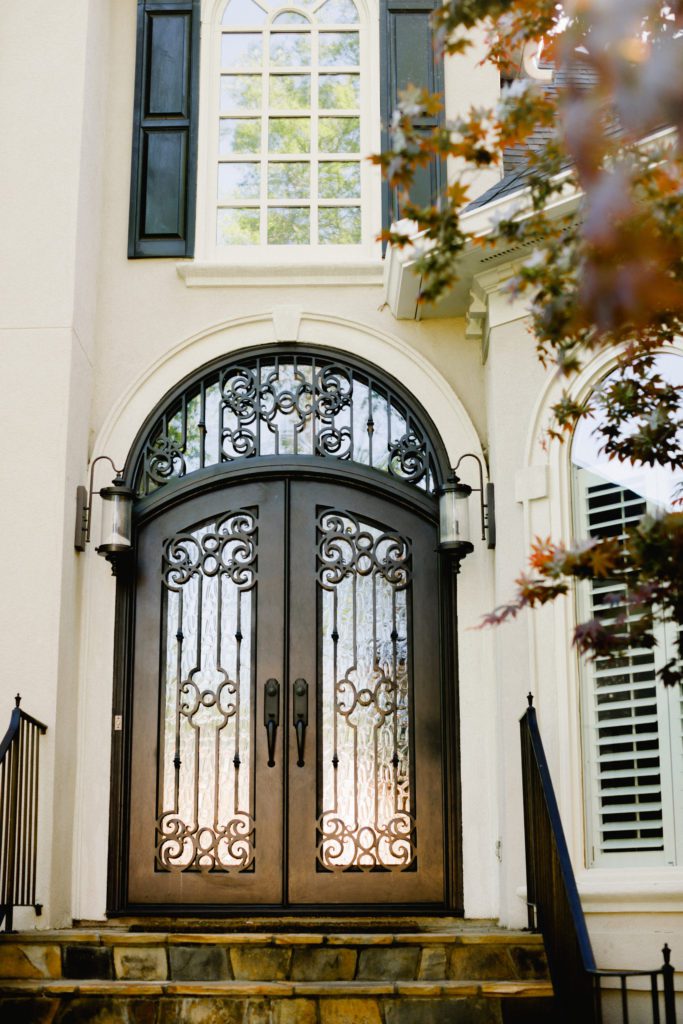 An ornate double iron door with a transom window..