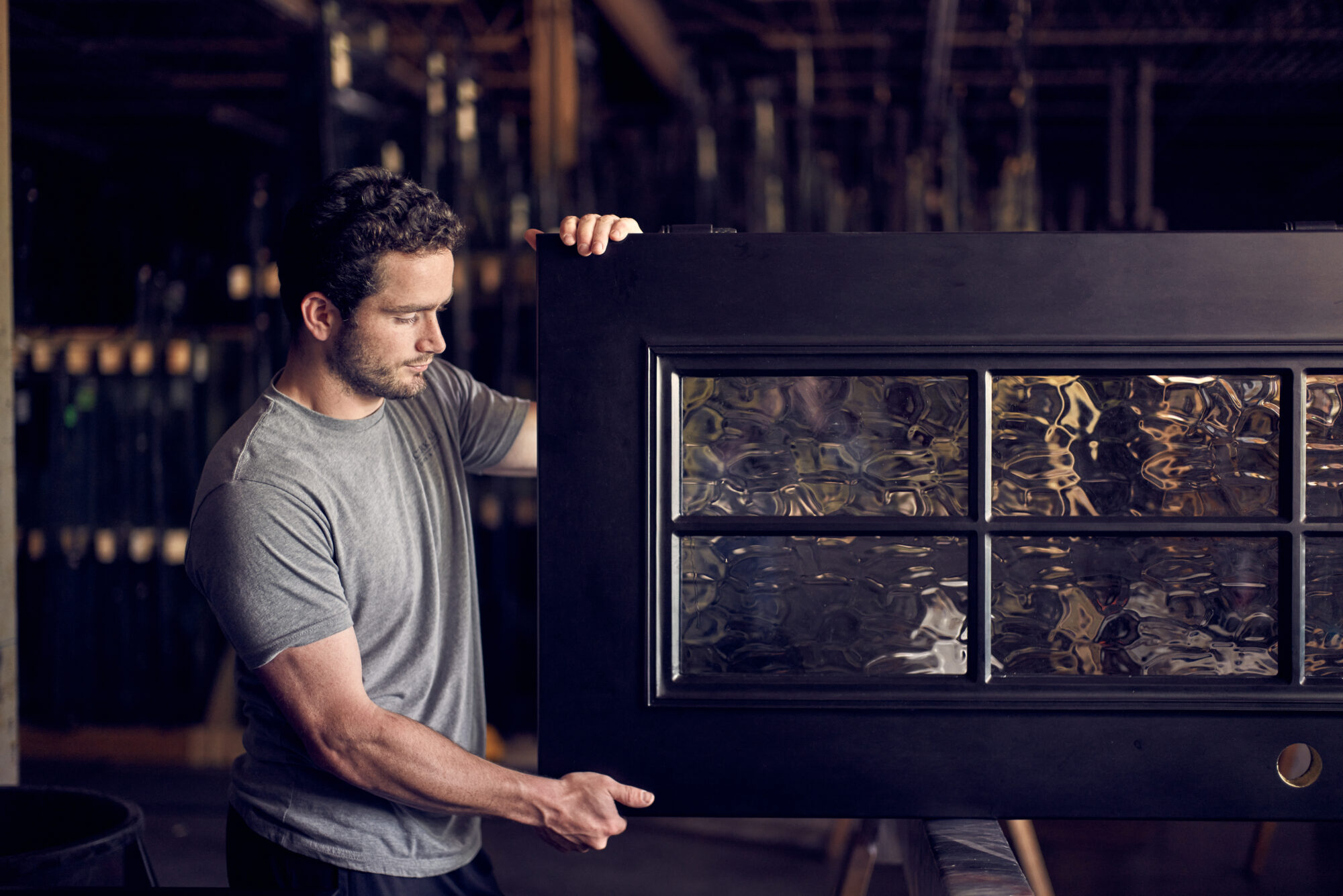 An artisan holds a finished custom iron door during the quality check process.