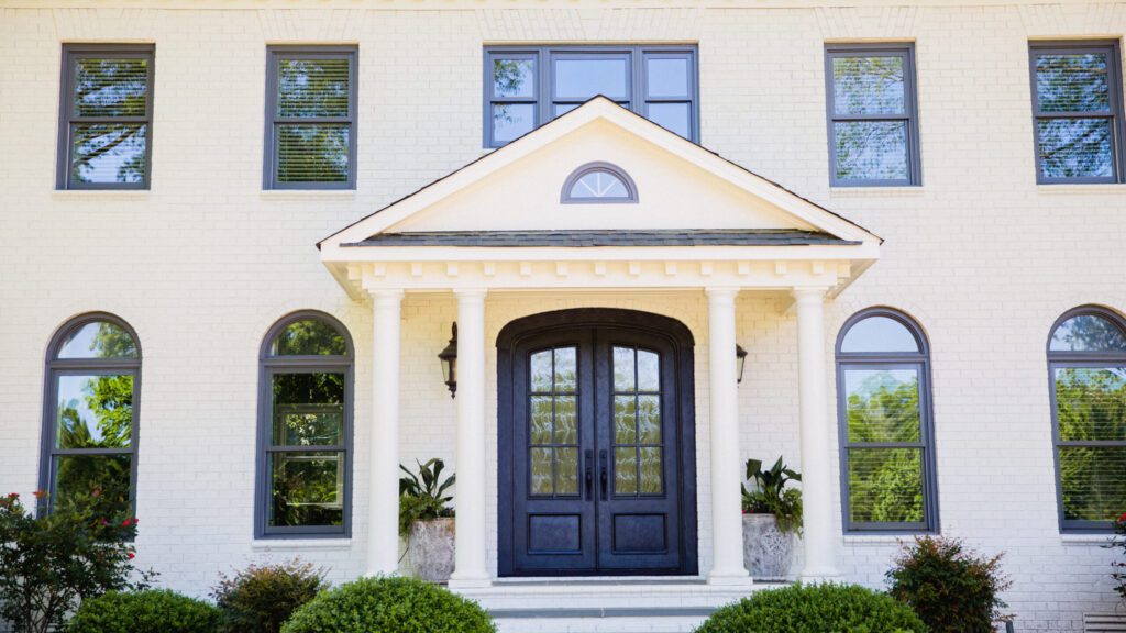 A white brick home with a traditional door style