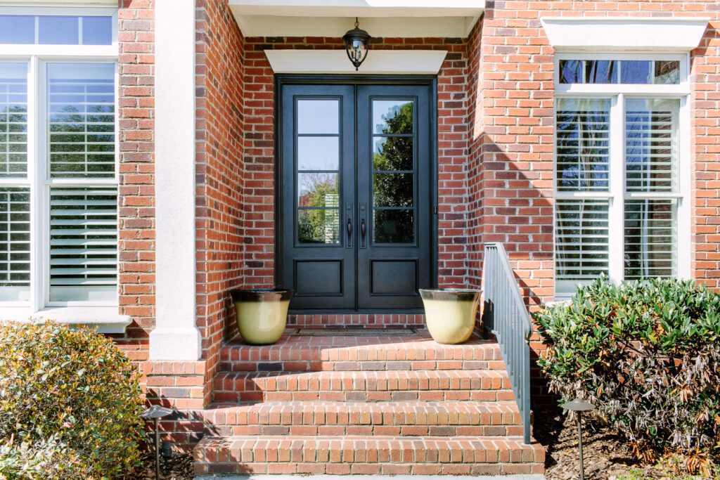 Charcoal double traditional style doors on a brick home.