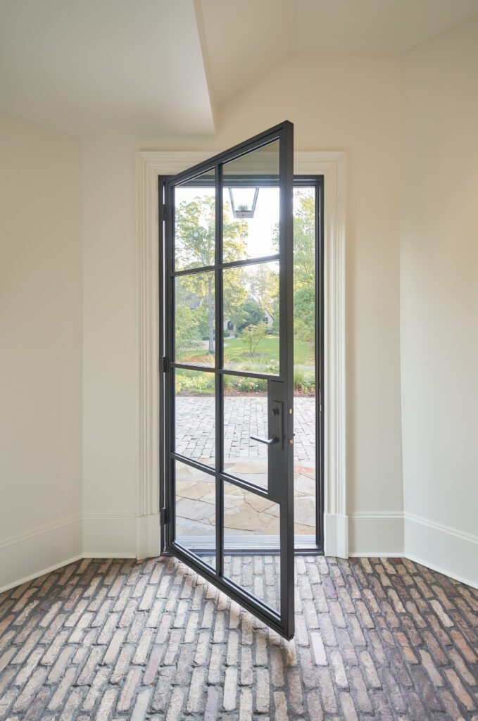 Partially open modern iron glass door leading to patio
