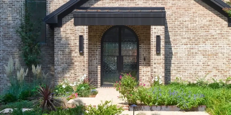 Black traditional iron glass door in brick themed house with front garden